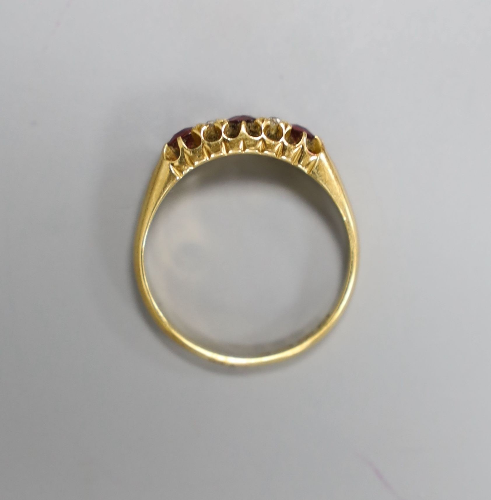 A late Victorian 18ct gold, three stone ruby and four stone diamond set half hoop ring, size M, gross 2.9 grams.